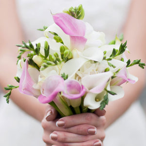 Hands holding bouquet of freesia & calla blend pastel lace